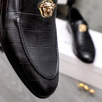Black leather loafer with gold lion emblem and curved moc toe seam
