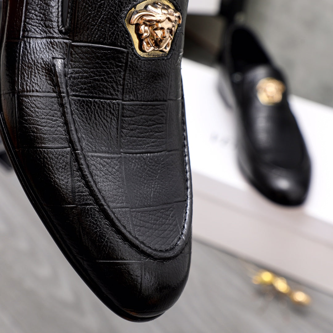 Black leather loafer with gold lion emblem and curved moc toe seam