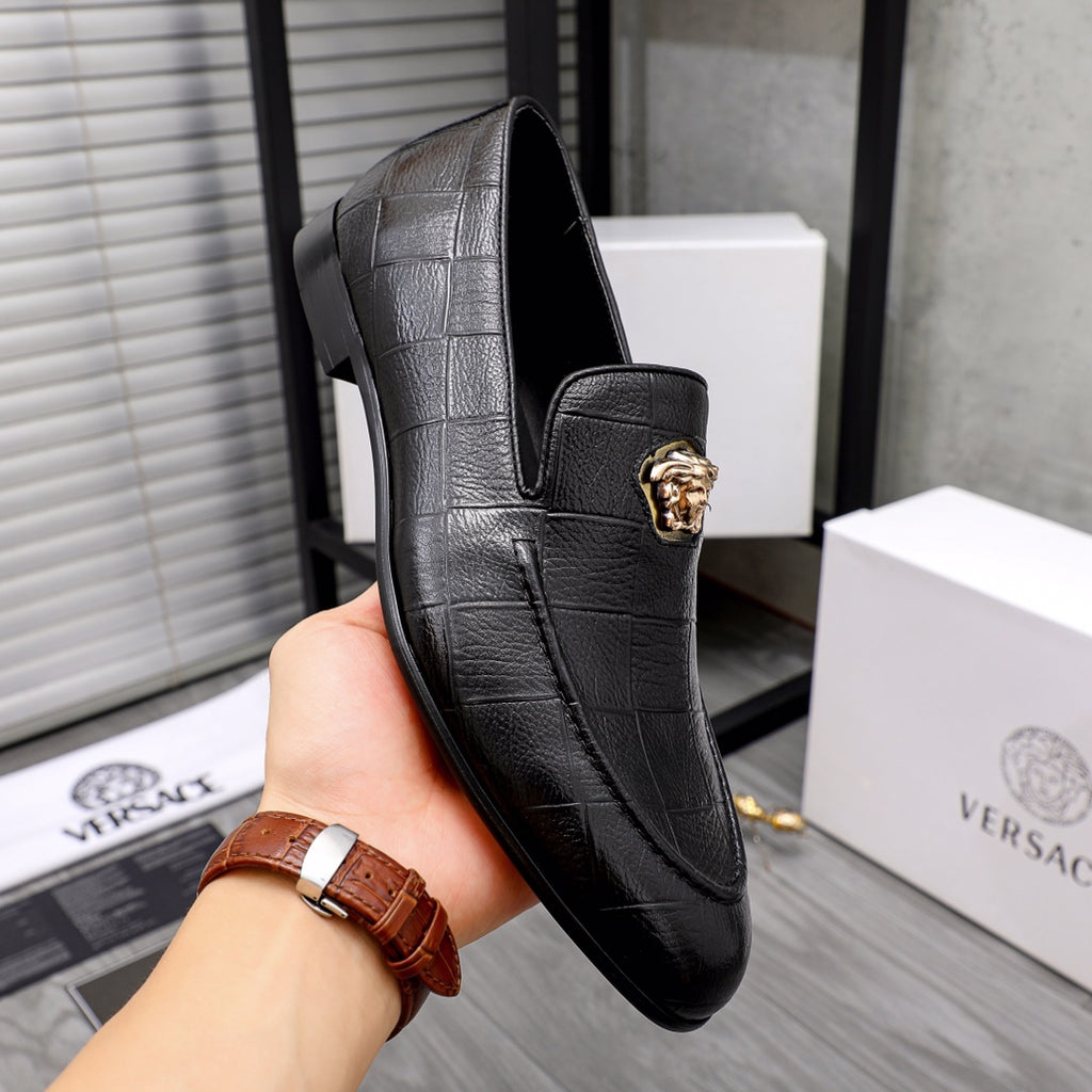 Black leather loafer with front gold emblem and textured panel stitching