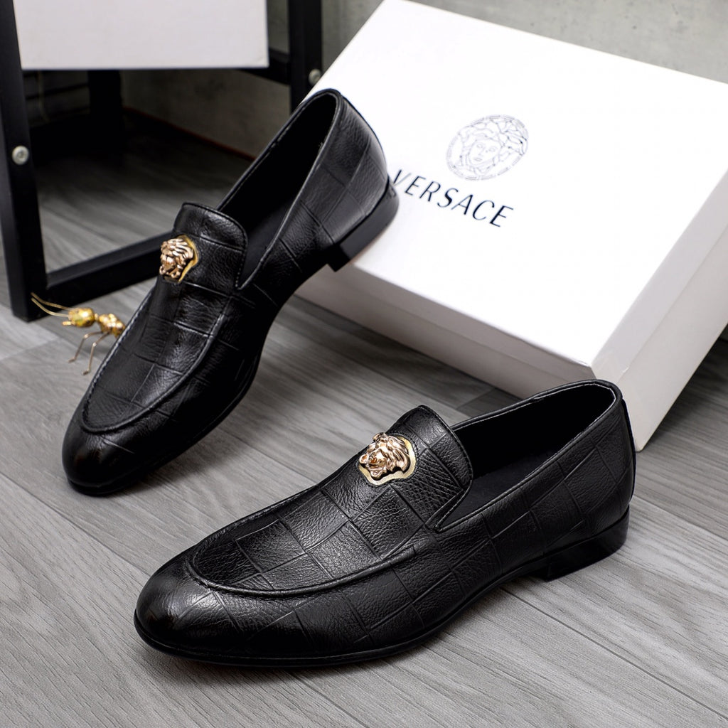 Pair of black leather loafers with gold emblems and slip-on design