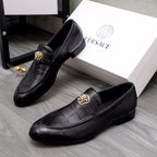 Pair of black leather loafers with gold emblems and slip-on design