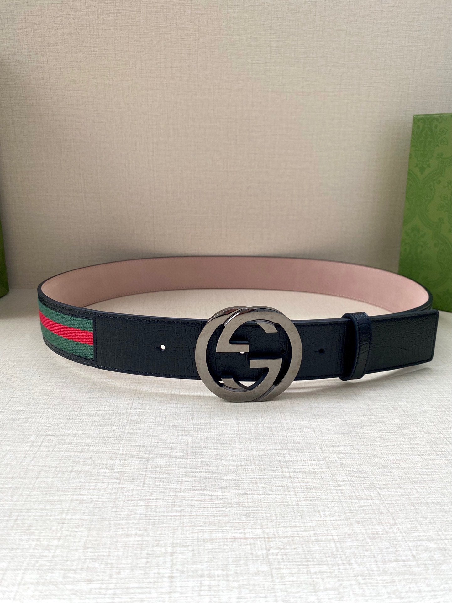 Gucci belt flat lay with dark blue leather strap and silver-tone double-G buckle.