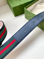 Gucci belt strap detail: textured dark blue leather with green-red-green stripe web.