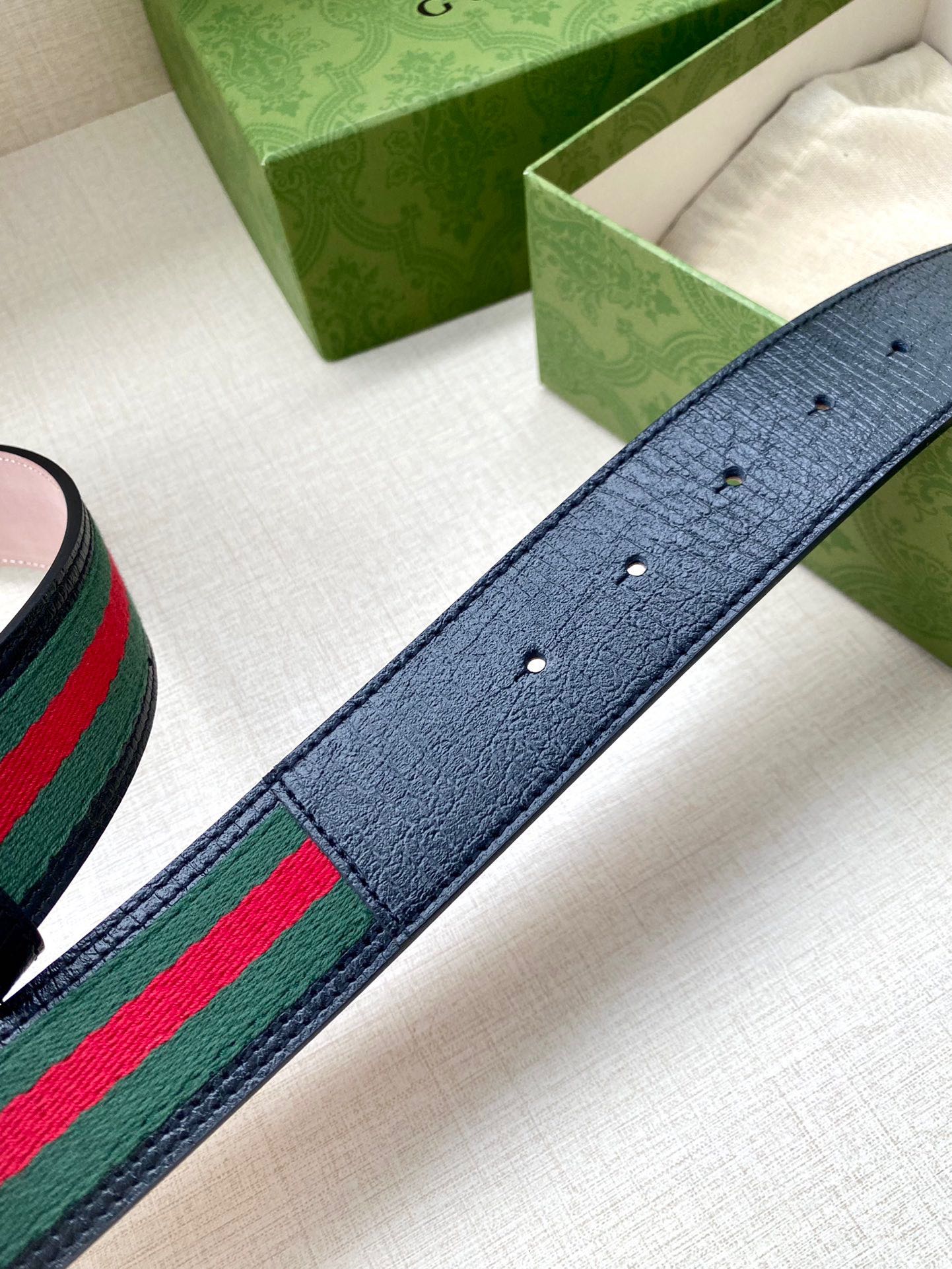 Gucci belt strap detail: textured dark blue leather with green-red-green stripe web.