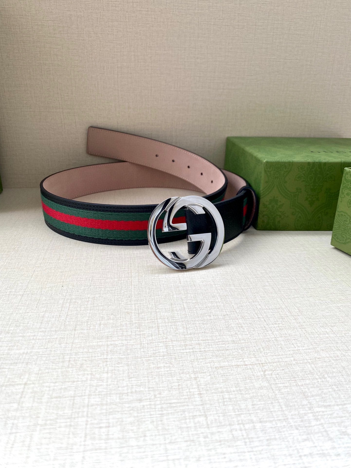 Gucci belt on display: dark blue strap with green-red stripe web and silver-tone buckle.