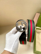 Gucci belt close-up: dark blue strap with silver-tone double-G buckle and green-red stripe web.