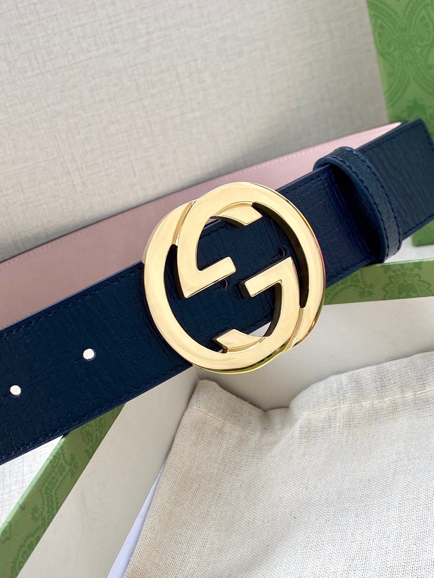 Gucci belt close-up: dark blue strap with gold-tone double-G buckle centerpiece.
