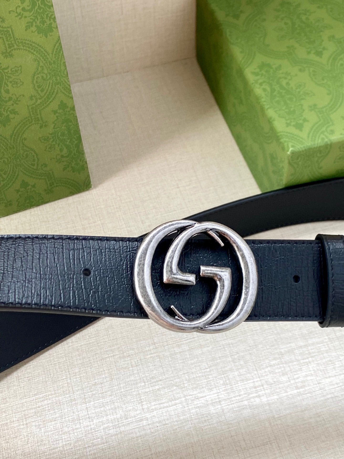 Navy leather belt with silver double-G buckle, button holes visible