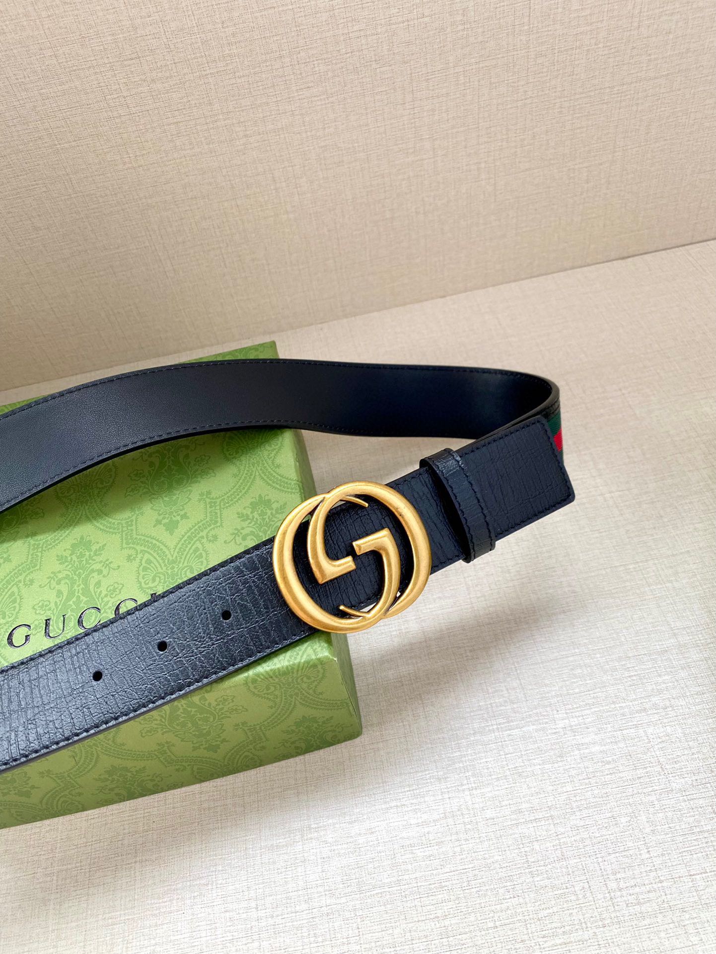 Navy leather belt detail with gold double-G buckle and striped edge