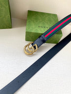 Gucci belt strap detail: gold double-G buckle on dark navy leather with green/red web stripe.