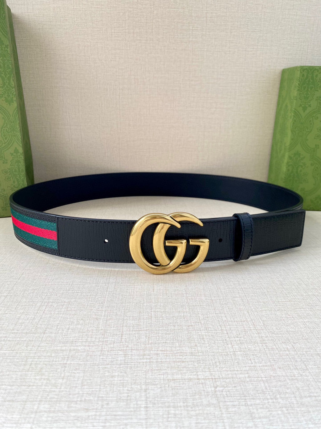 Gucci belt: dark navy leather strap, gold double-G buckle, green/red web trim.