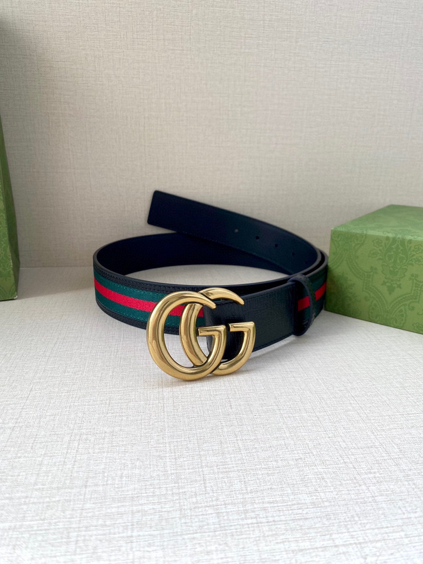Gucci belt, front view: dark navy strap with gold double-G buckle and green/red web trim.