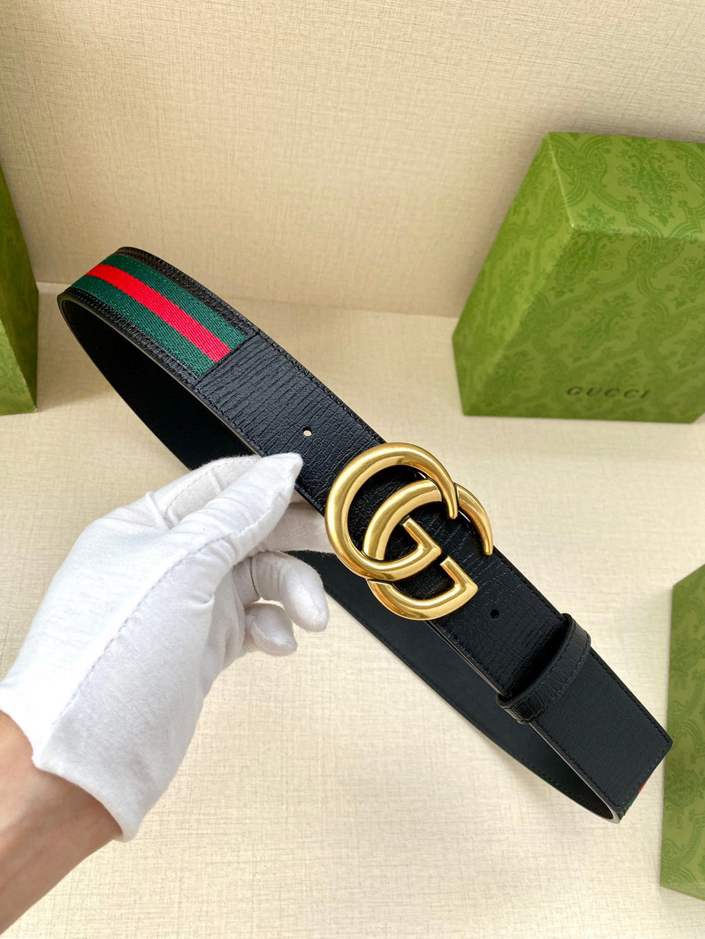 Gucci belt in hand: dark navy leather with gold double-G buckle and green/red web stripe.