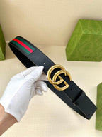 Gucci belt in hand: dark navy leather with gold double-G buckle and green/red web stripe.