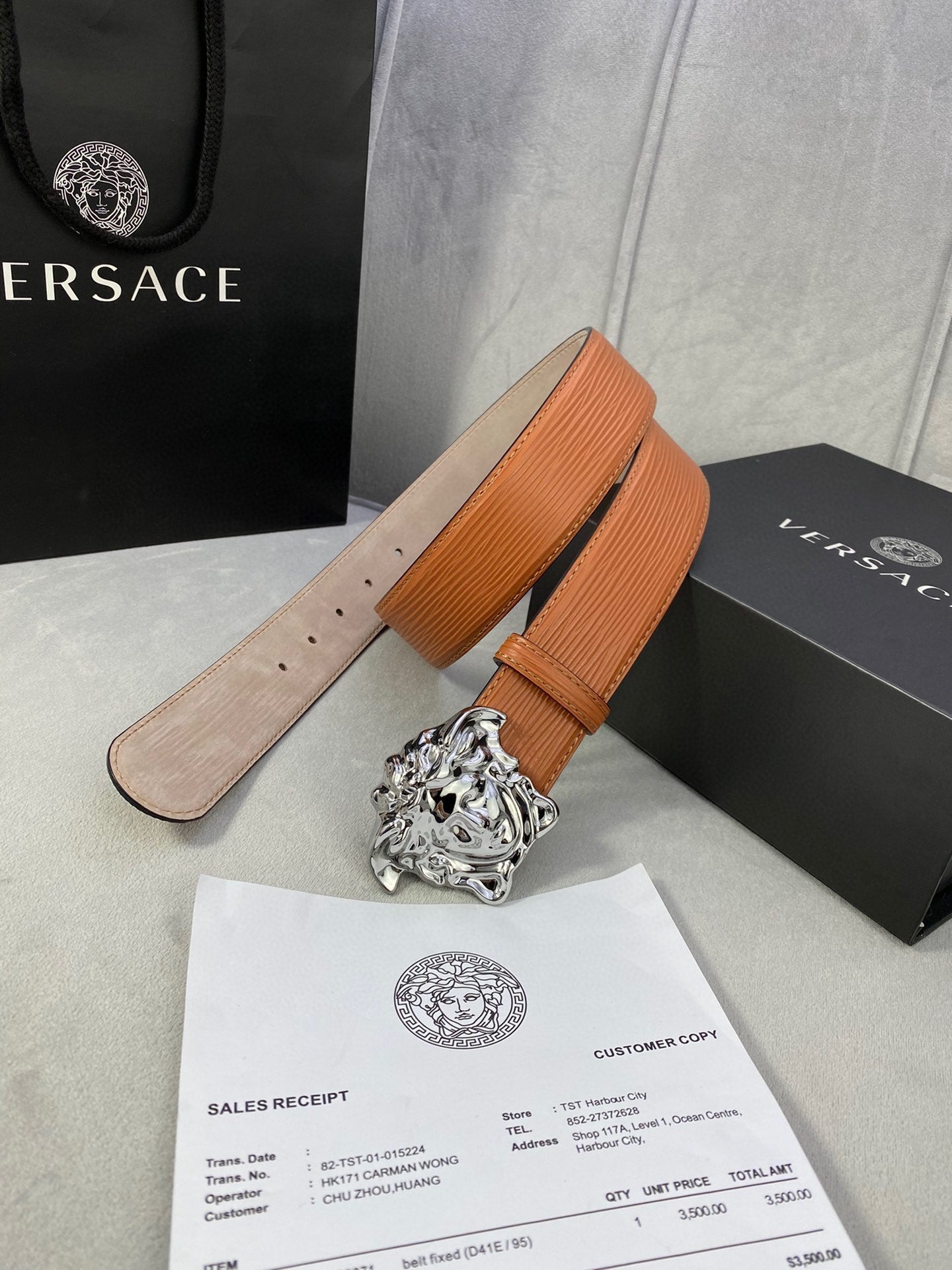 Orange leather belt with silver-toned Medusa buckle and curved strap end