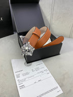 Orange leather belt with silver-toned Medusa buckle resting in a black box