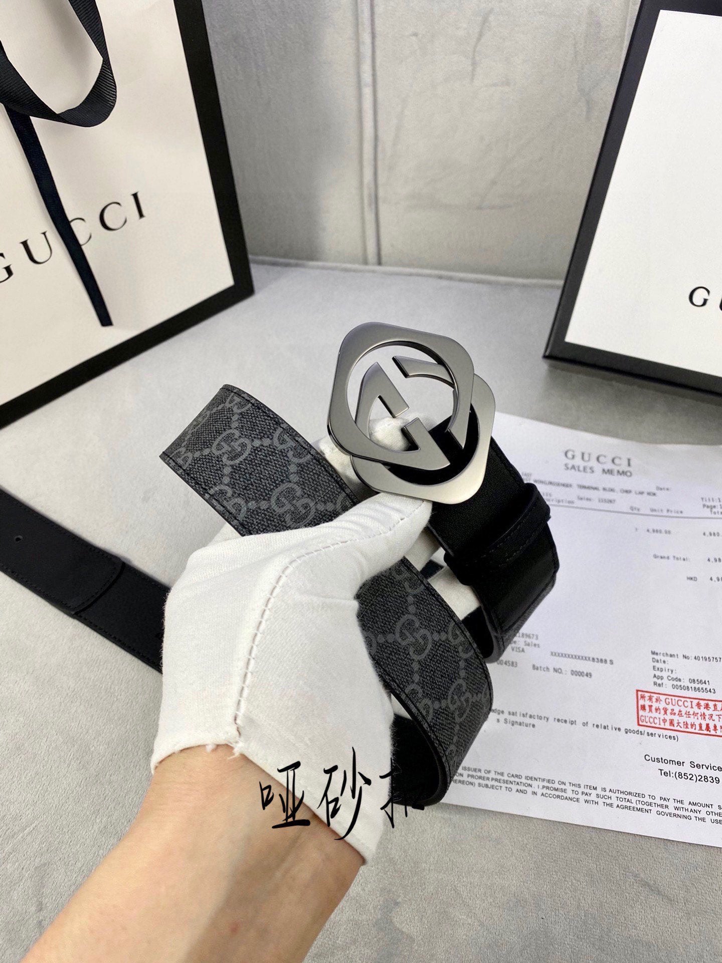 Black Gucci belt with GG monogram strap and large silver-tone interlocking buckle.