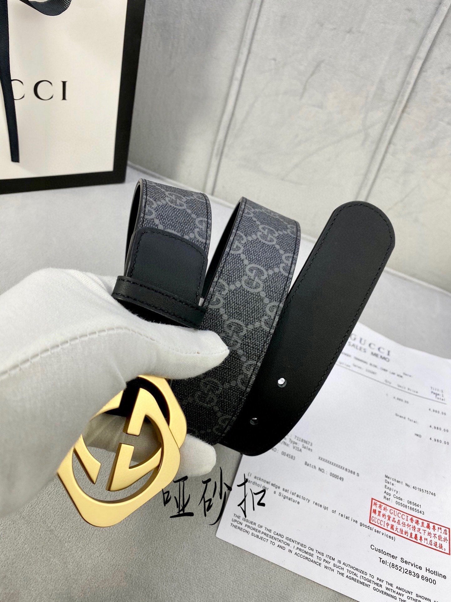 Black Gucci belt with GG monogram strap and gold-tone interlocking buckle close-up.