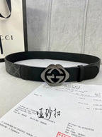 Black Gucci belt with dark GG monogram strap and silver-tone GG buckle.