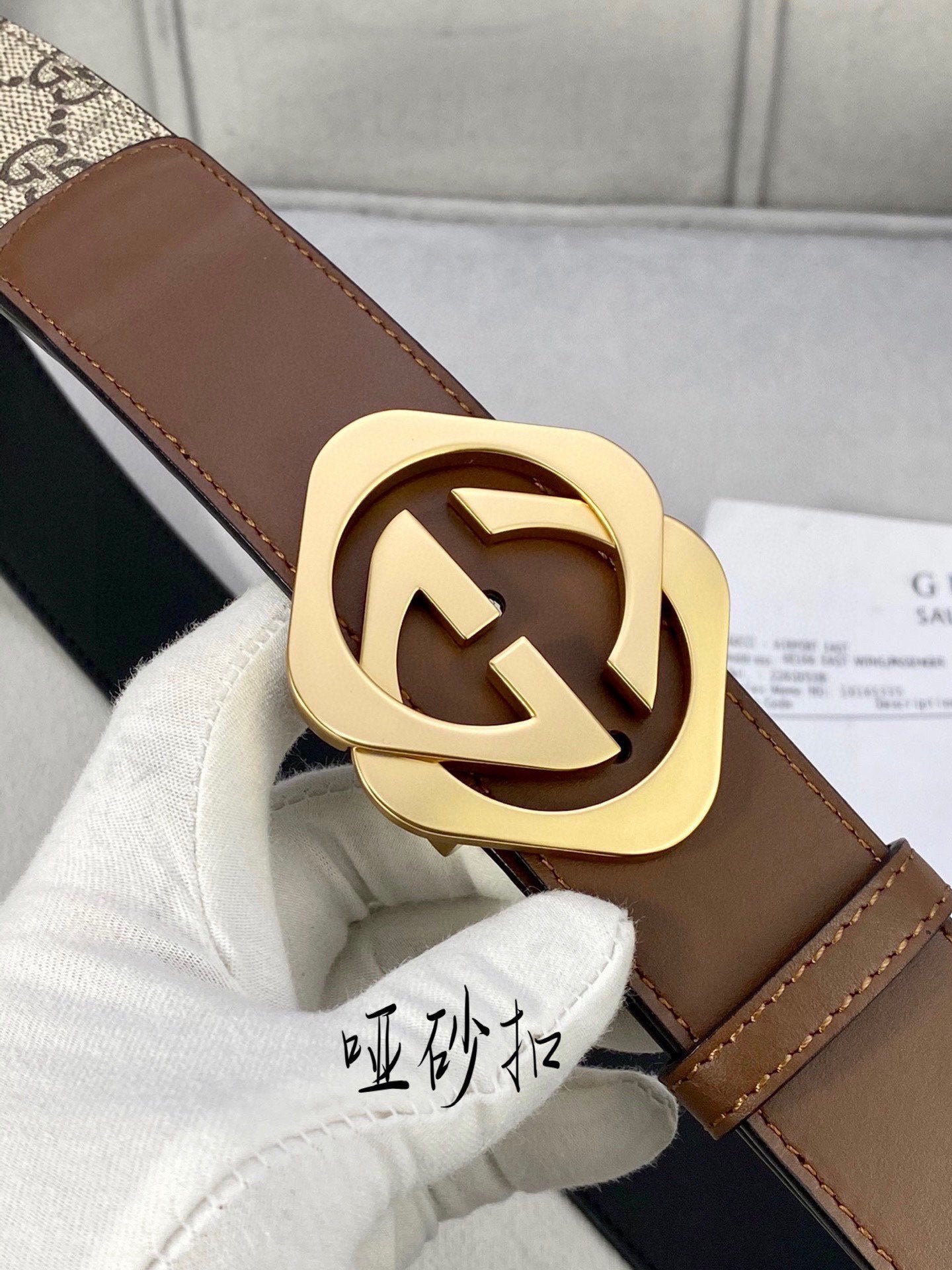 Gucci belt buckle close-up: gold-tone double-G on brown leather strap and GG canvas.