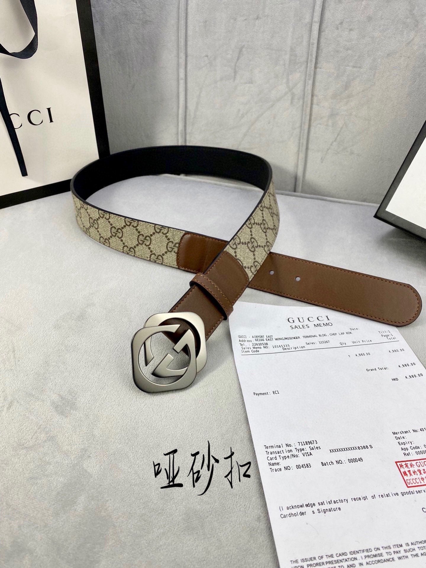 Gucci belt with GG-pattern canvas strap and brown leather, silver-tone buckle detail.