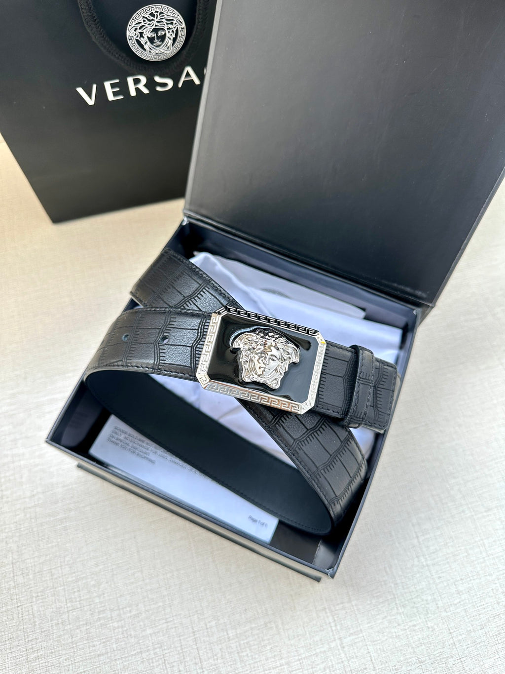 Navy leather belt with embossed texture and gold Medusa buckle in box