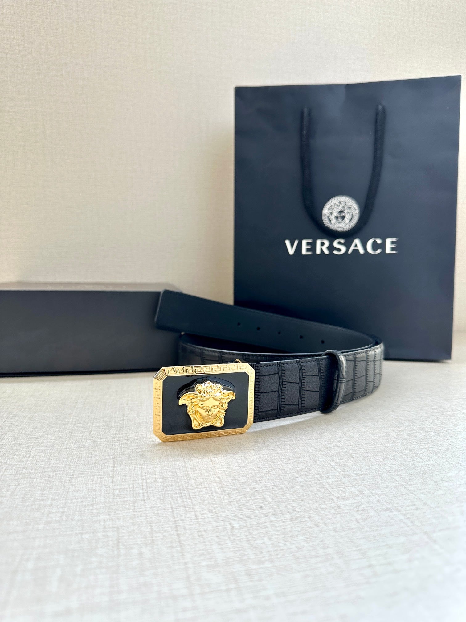 Navy leather belt with embossed finish and gold Medusa buckle centerpiece
