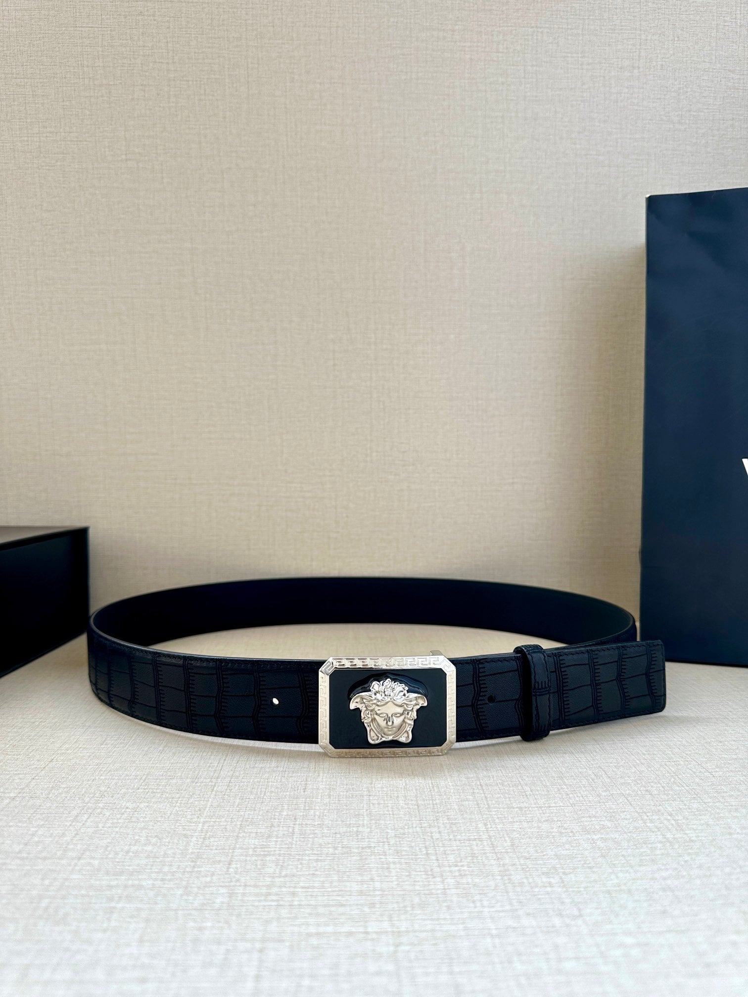 Navy leather belt with embossed texture and gold Medusa buckle at center