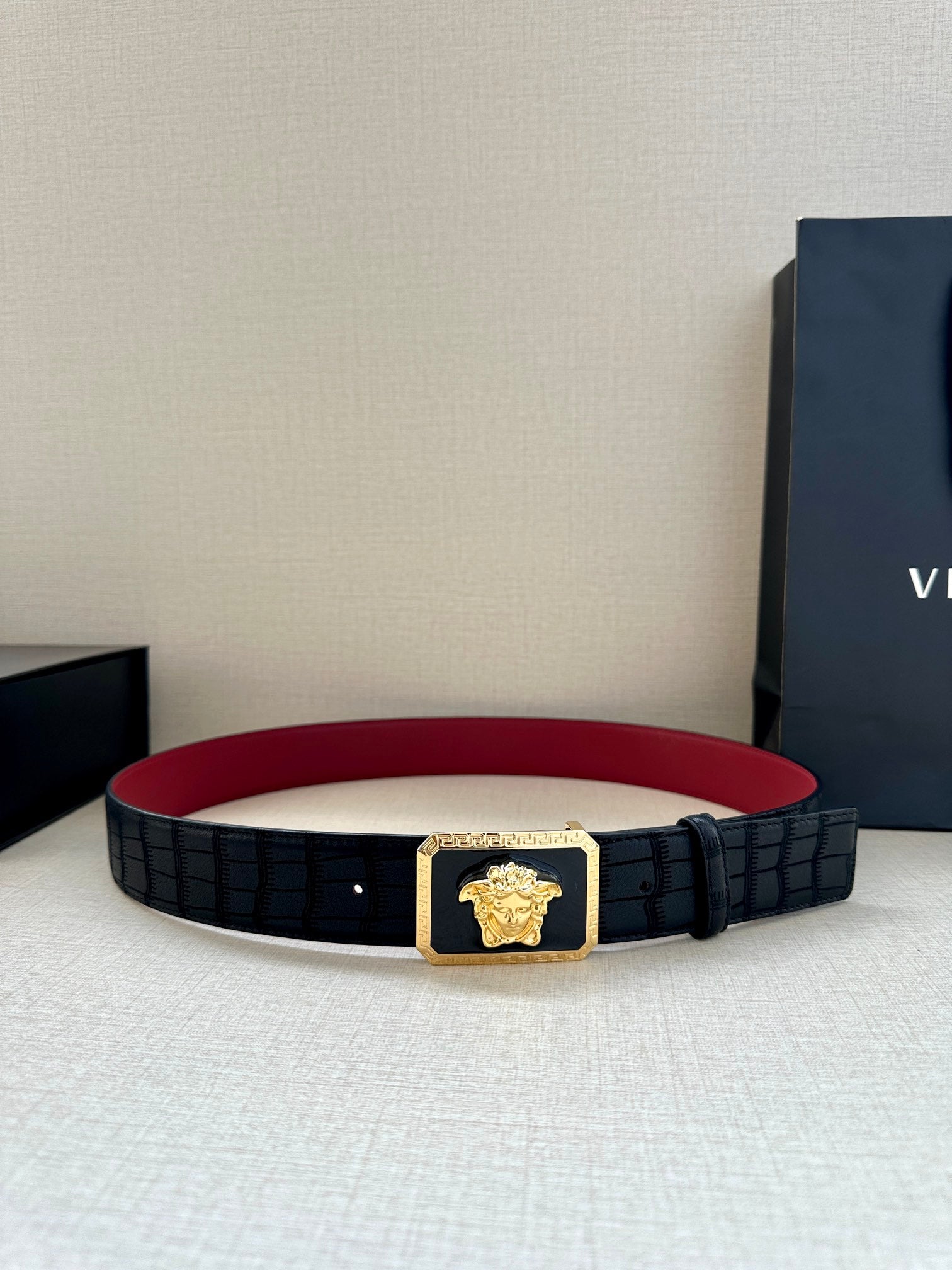 Belt: black textured belt with gold Medusa buckle and red underside lining.