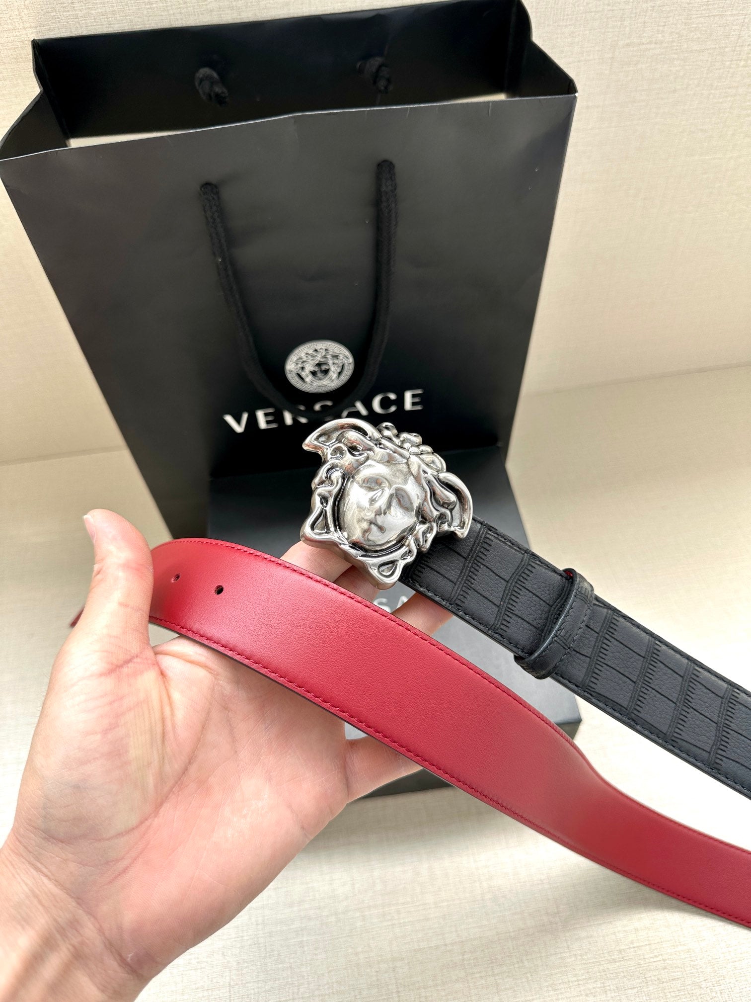Red leather belt with black crosshatch strap and silver Medusa buckle