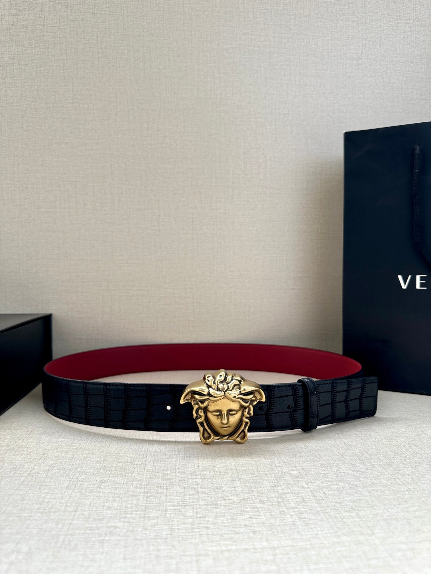 Black leather belt with gold Medusa buckle and red underside