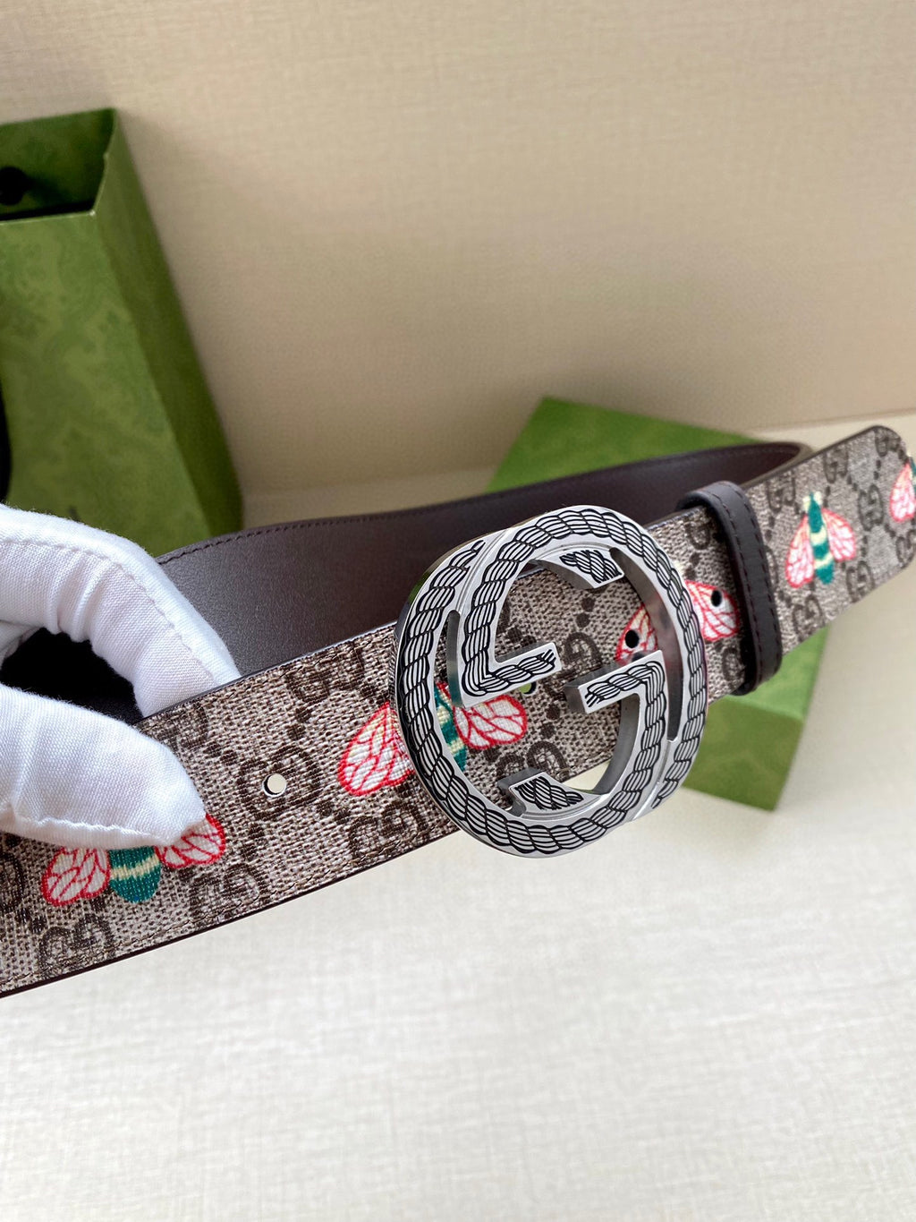 Gucci belt close-up: GG logo canvas strap with floral motifs and dark leather, round buckle