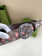 Gucci belt close-up: GG logo canvas strap with floral motifs and dark leather, round buckle