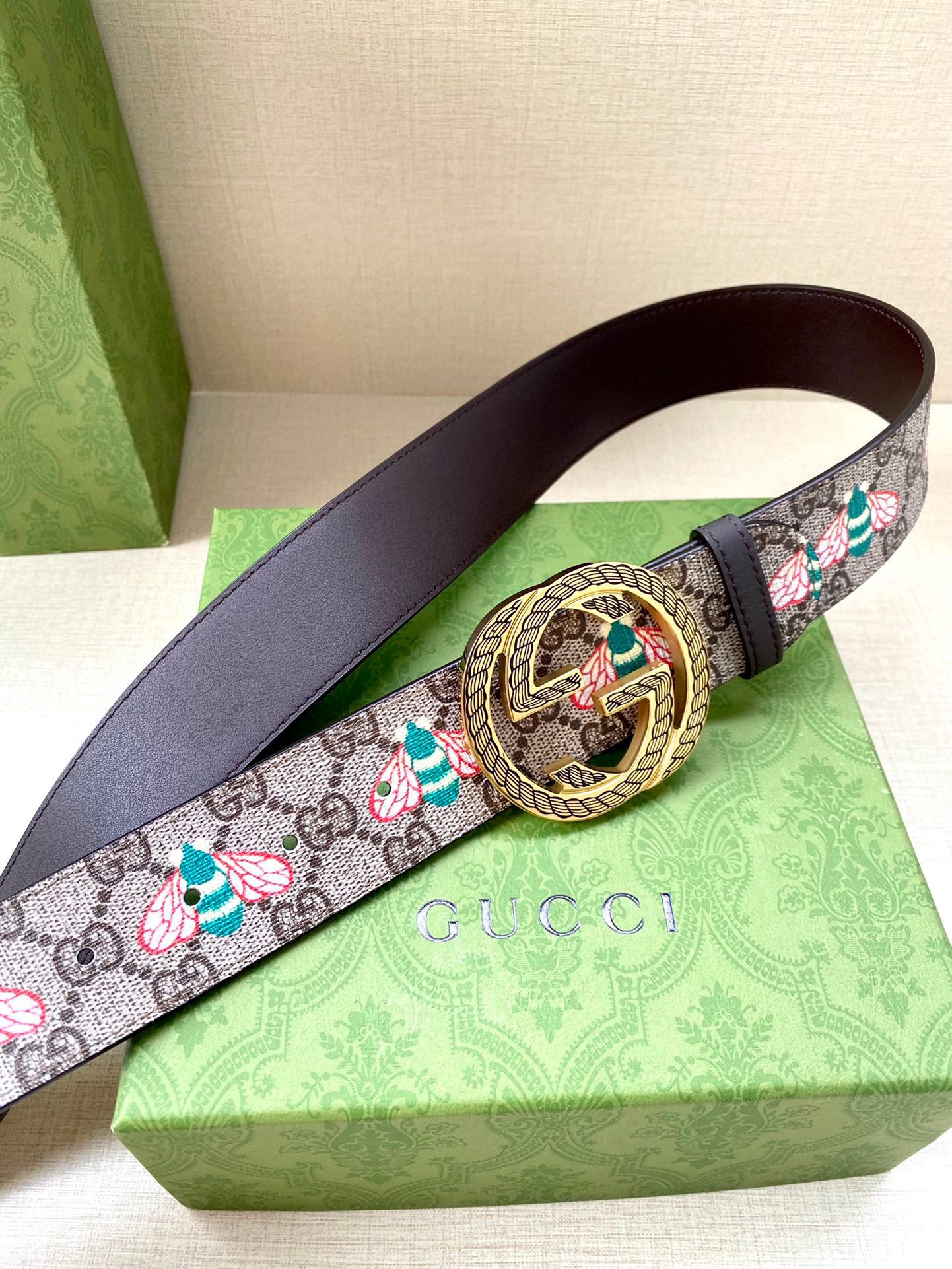 Gucci belt with GG canvas floral pattern and dark leather strap, gold-toned round buckle