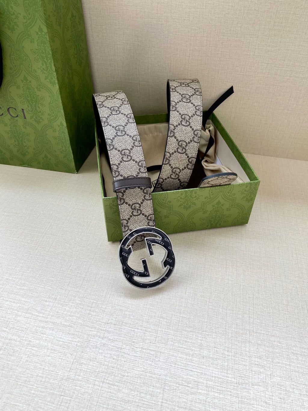 Gucci belt with GG monogram canvas strap and dark buckle, standing upright