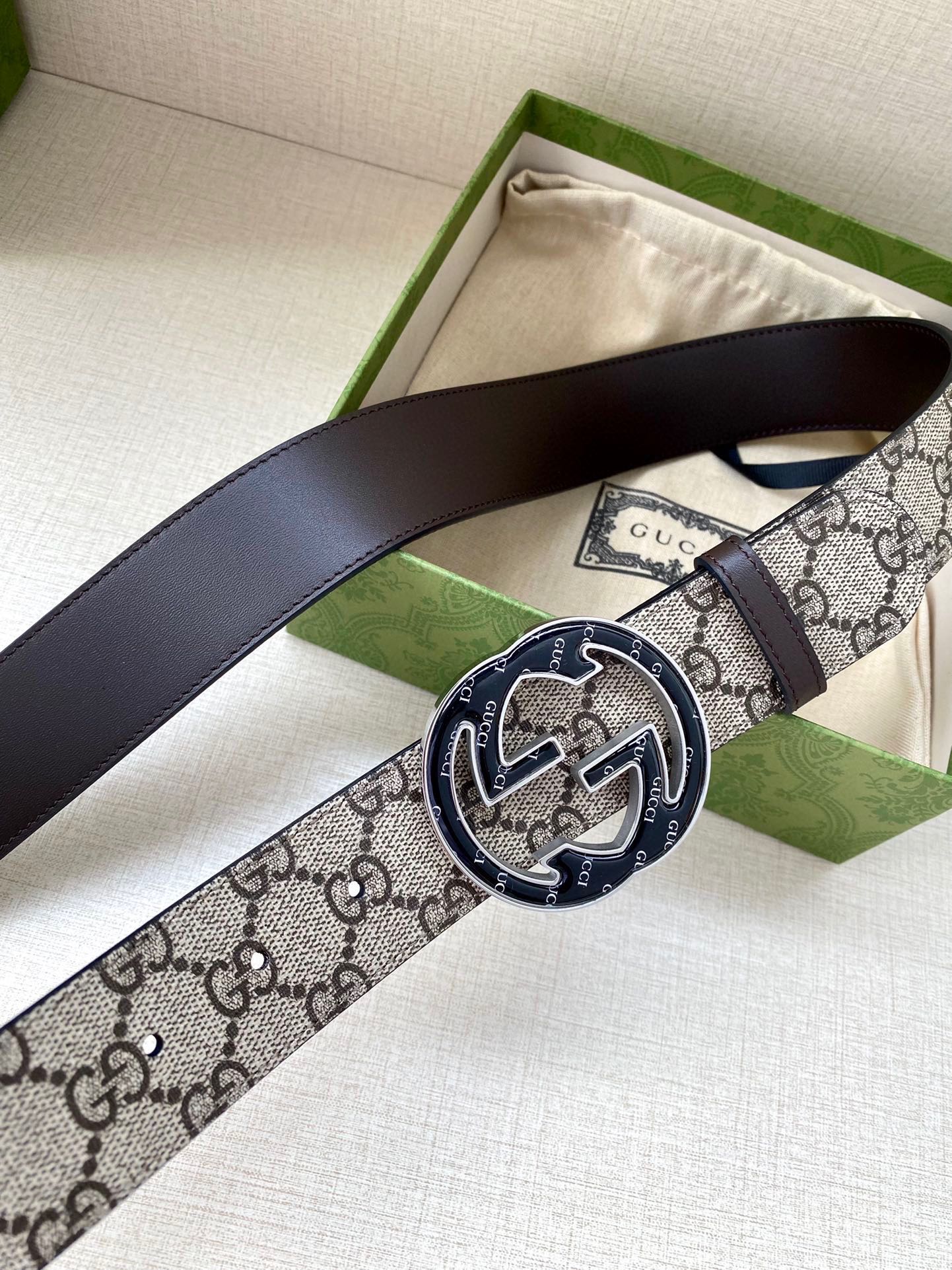 Gucci belt with dark leather strap and GG monogram buckle centerpiece