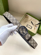 Gucci belt with GG monogram canvas strap and dark metal oval buckle, held in hand