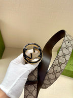 Gucci belt close-up of round gold buckle with interlocking horse motif on GG strap