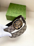Gucci belt with GG monogram strap and large gold-tone horse buckle, held up
