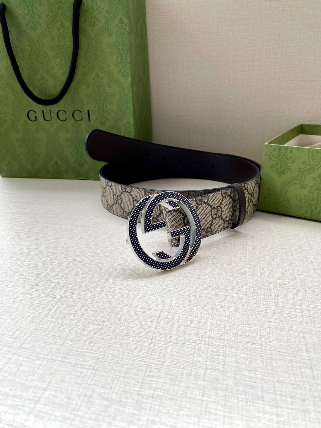 Gucci belt with GG monogram canvas and dark leather buckle, folded on display