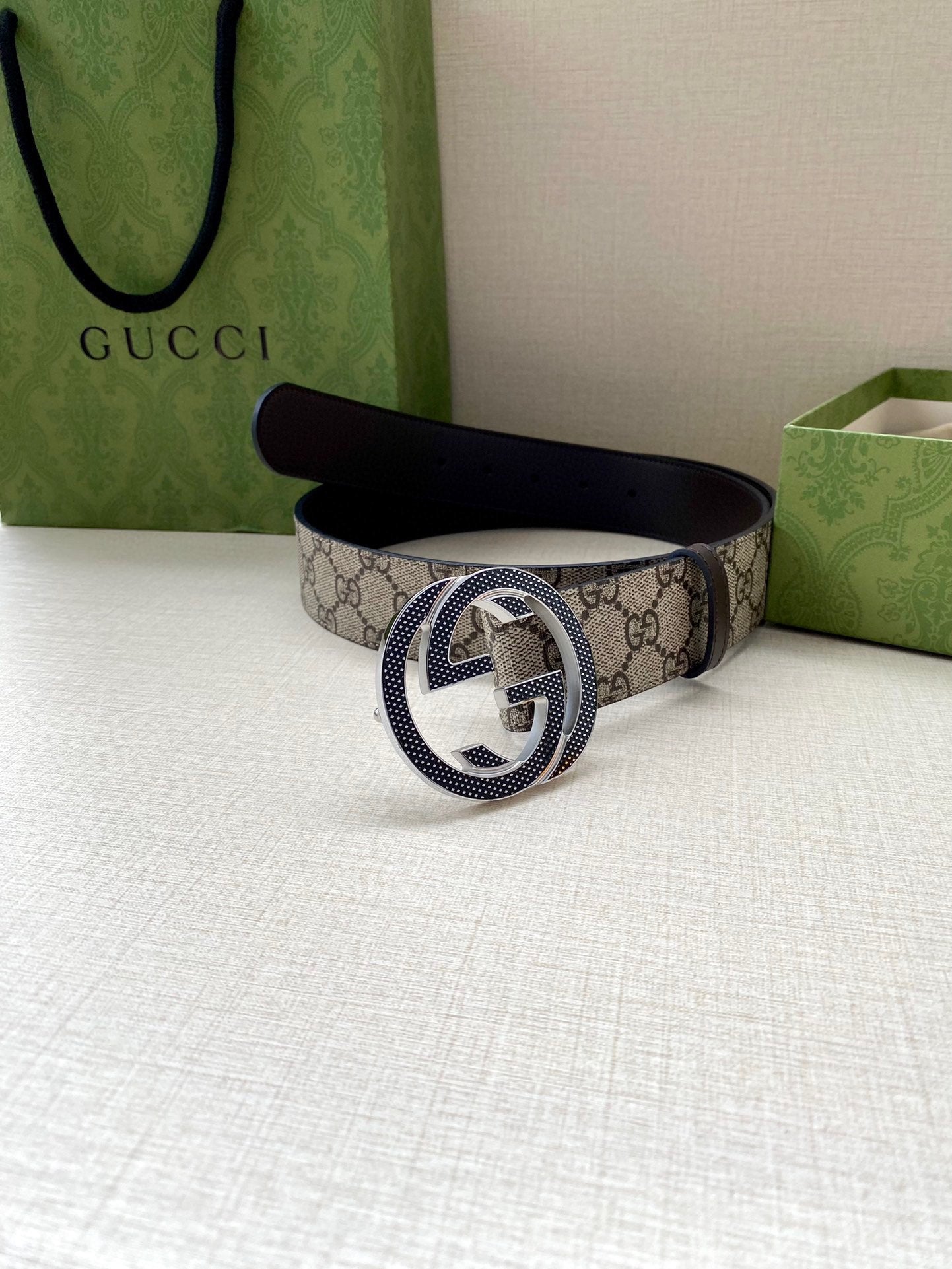 Gucci belt with GG monogram canvas and dark leather buckle, folded on display