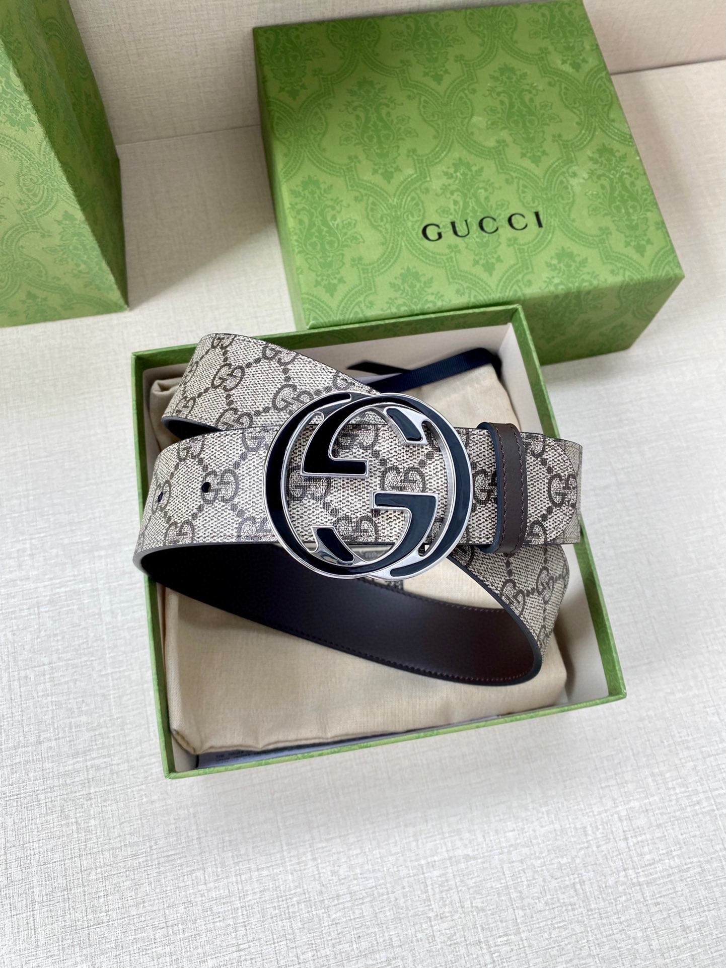 Gucci belt featuring GG monogram canvas and dark leather strap with large logo buckle