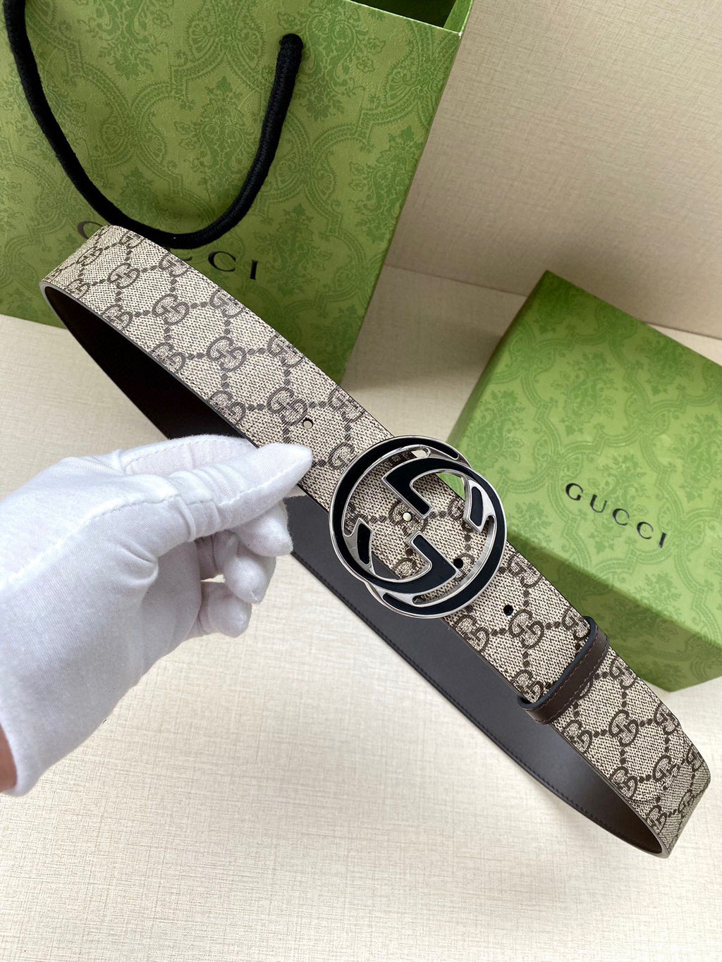 Gucci belt with GG canvas print strap and dark leather underside, featuring a silver buckle