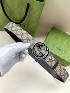 Gucci belt with GG canvas print strap and dark leather underside, featuring a silver buckle