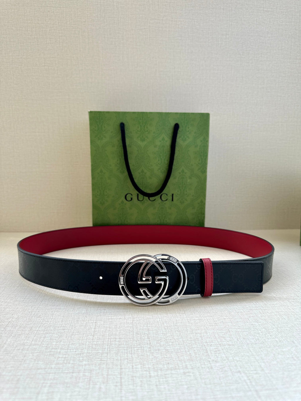 Gucci logo belt with round GG buckle, dark navy strap and red belt lining
