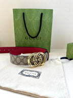 Gucci belt on cloth with green gift bag: gray GG monogram strap and gold-tone GG buckle