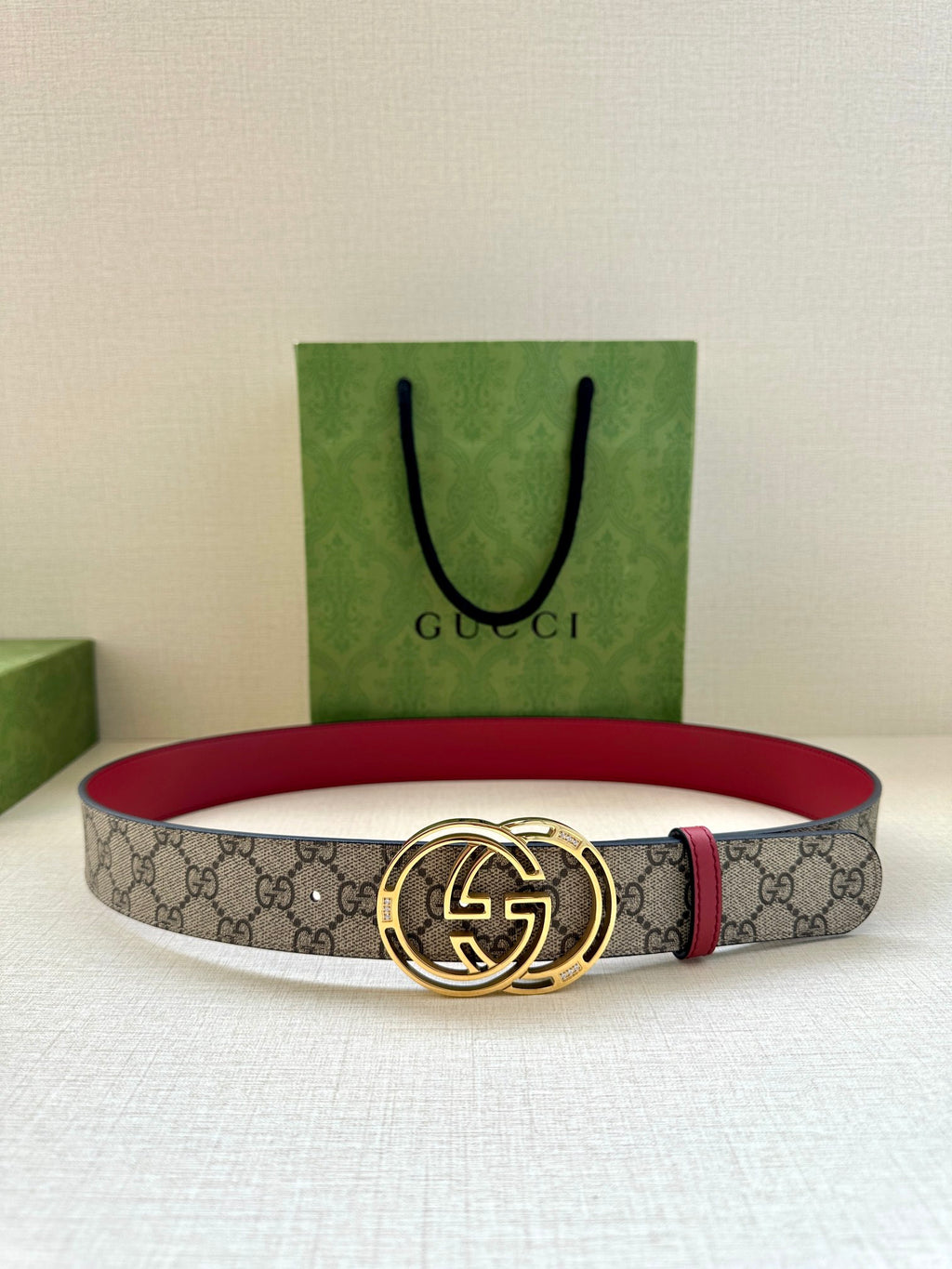 Gucci belt with gray GG monogram strap, red leather trim, and gold-tone GG buckle