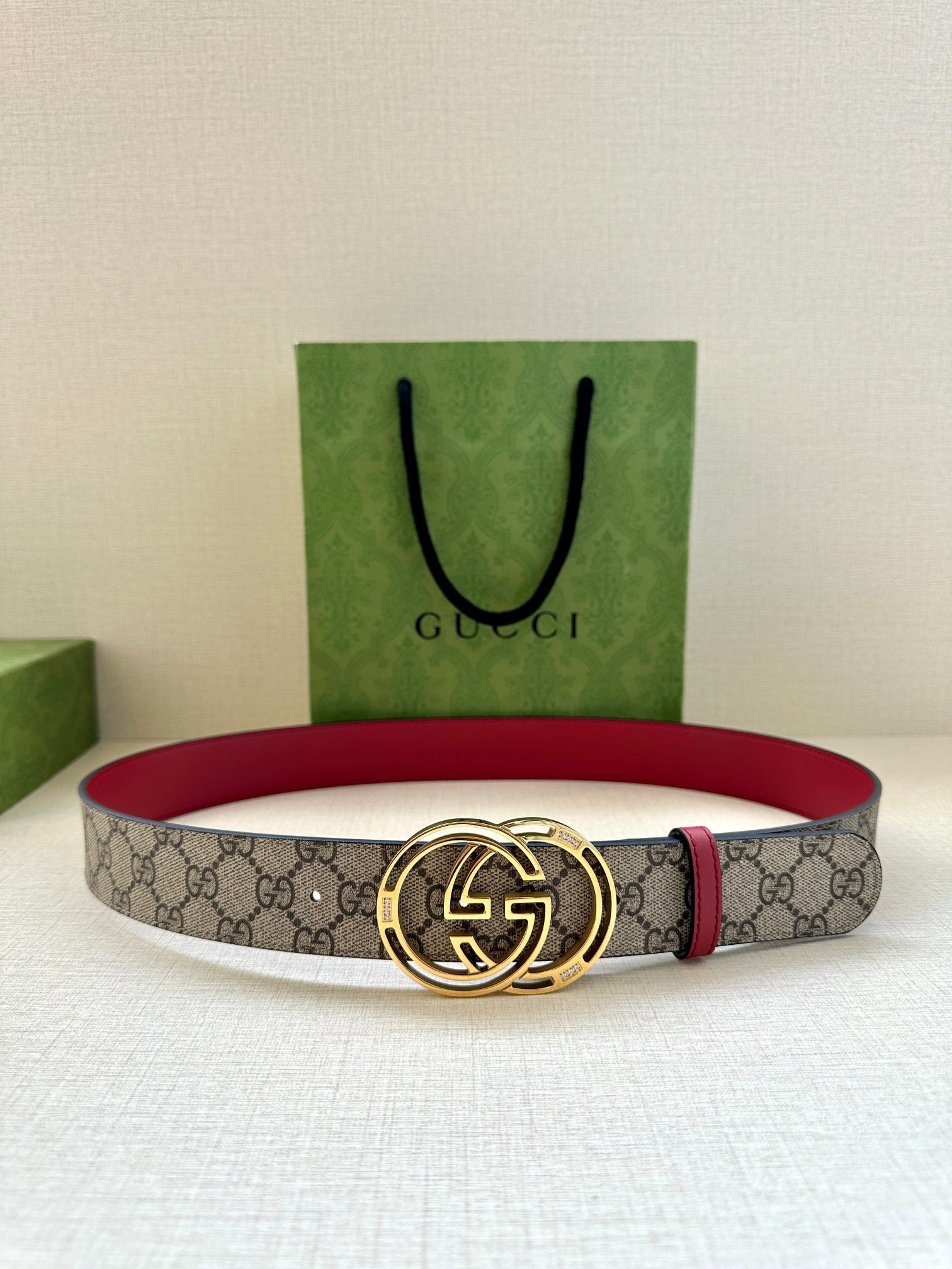 Gucci belt with gray GG monogram strap, red leather trim, and gold-tone GG buckle