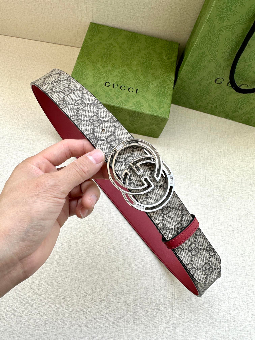 Gucci belt with gray GG monogram strap, red edge, and silver-tone GG buckle close-up