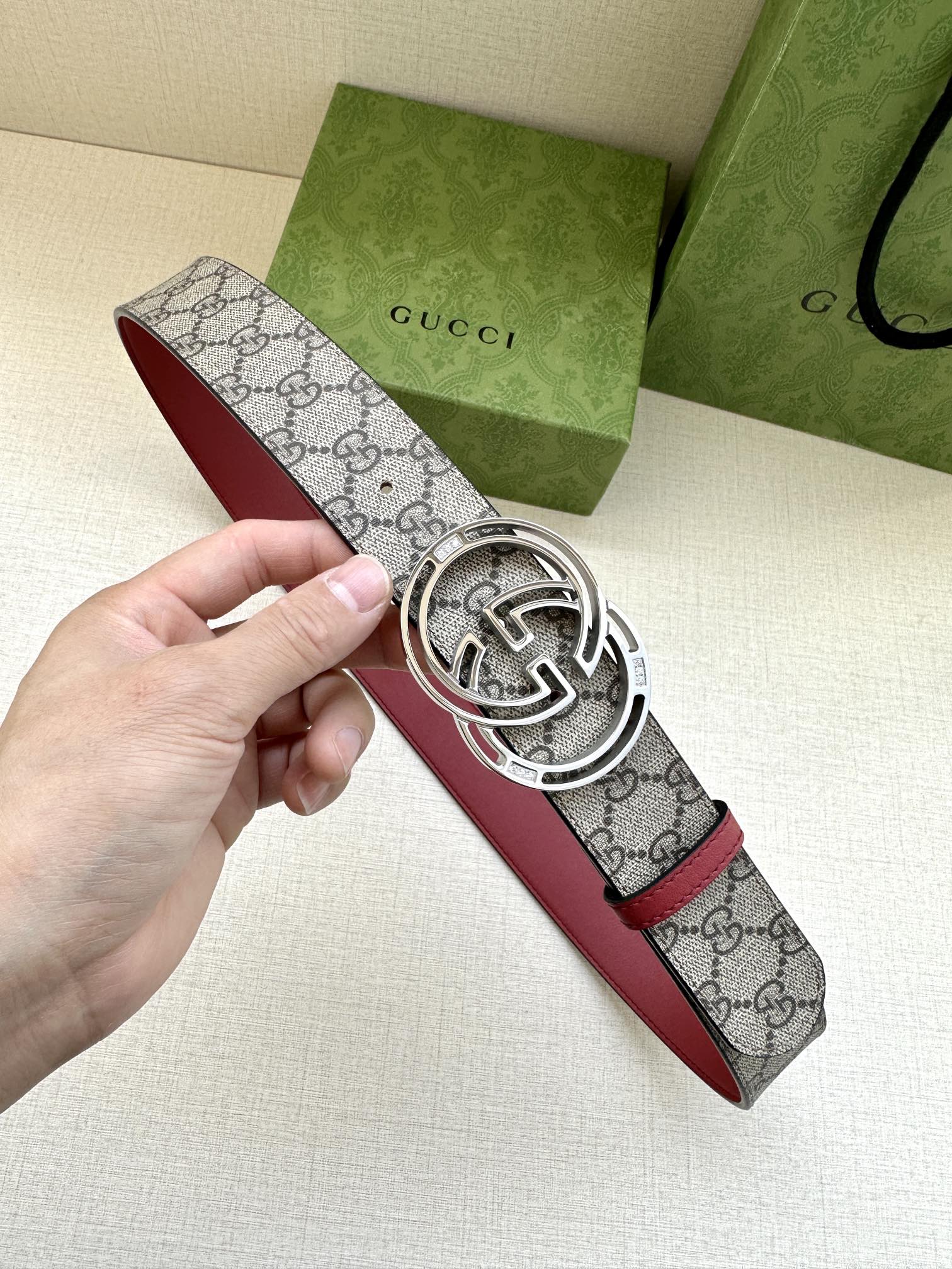 Gucci belt with gray GG monogram strap, red edge, and silver-tone GG buckle close-up